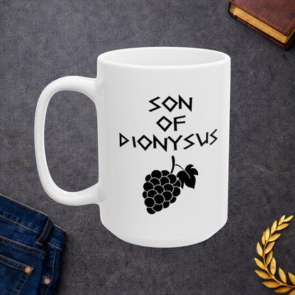 White ceramic mug featuring a minimalist, Greek-inspired graphic in black ink on a white background. The design reads 'SON OF DIONYSUS' in a stylized, angular font, positioned above a clean, line-art graphic of a cluster of grapes hanging from a vine with leaves.