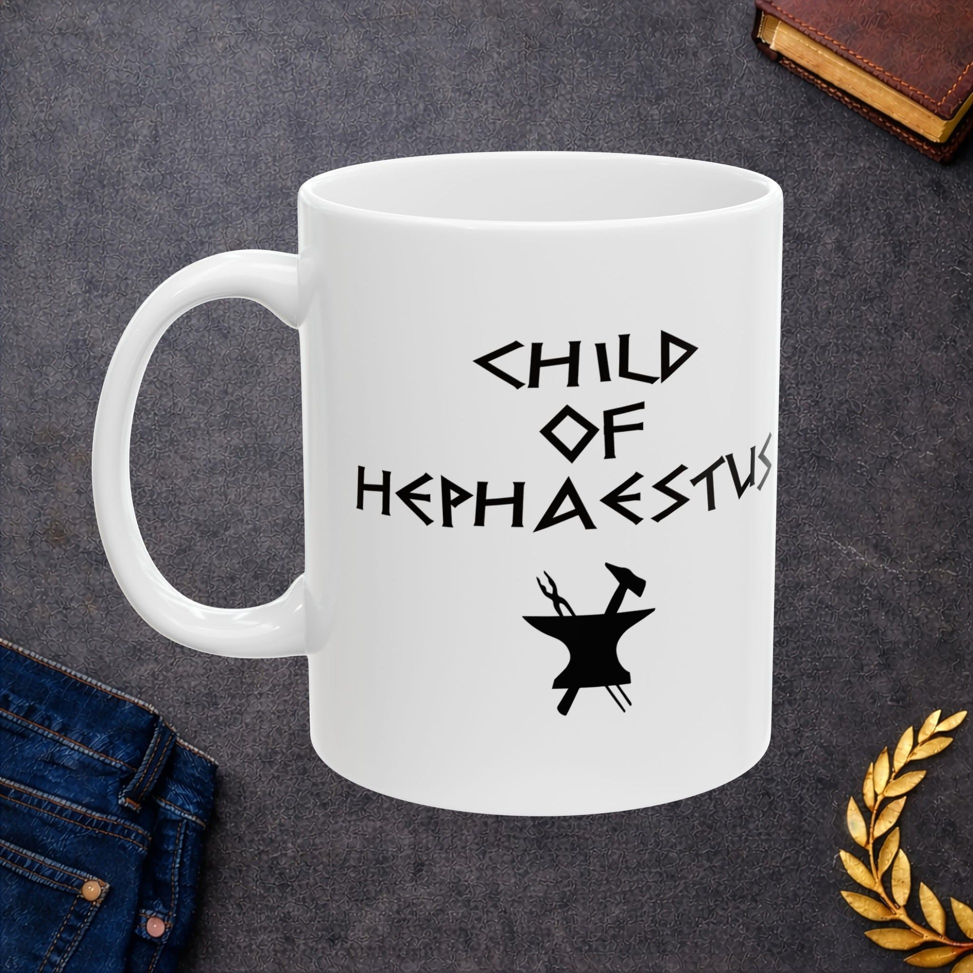 A minimalist black graphic for a white ceramic mug. The design features a central silhouette of a blacksmith's anvil with a hammer and tongs crossed behind it. Above the tools, the text "CHILD OF HEPHAESTUS" is written in a sharp, angular font inspired by ancient Greek inscriptions. The entire illustration is rendered in a clean, solid black style.