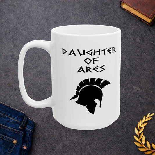 White ceramic mug featuring a minimalist, Greek-inspired graphic in black ink on a white background. The design reads 'DAUGHTER OF ARES' in a stylized, angular font, positioned above a clean, line-art graphic of a Spartan-style plumed warrior helmet.
