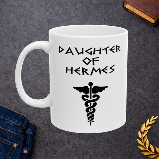 A minimalist black graphic for a white ceramic mug featuring a central caduceus symbol—a winged staff with two snakes entwined around it. Above the symbol, the text "DAUGHTER OF HERMES" is displayed in a sharp, angular font inspired by ancient Greek stone carvings. The entire design is rendered in a clean, high-contrast black outline.