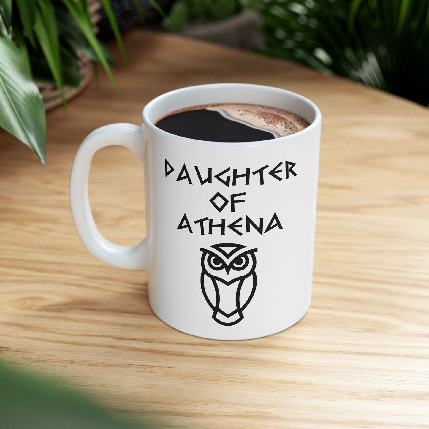 White ceramic mug graphic featuring bold ancient Greek-style lettering reading "Daughter of Athena" above a clean geometric line-art owl icon — referencing Athena, the Greek Goddess of Wisdom, whose sacred symbol is the owl, rendered in white on black in a striking high-contrast design.