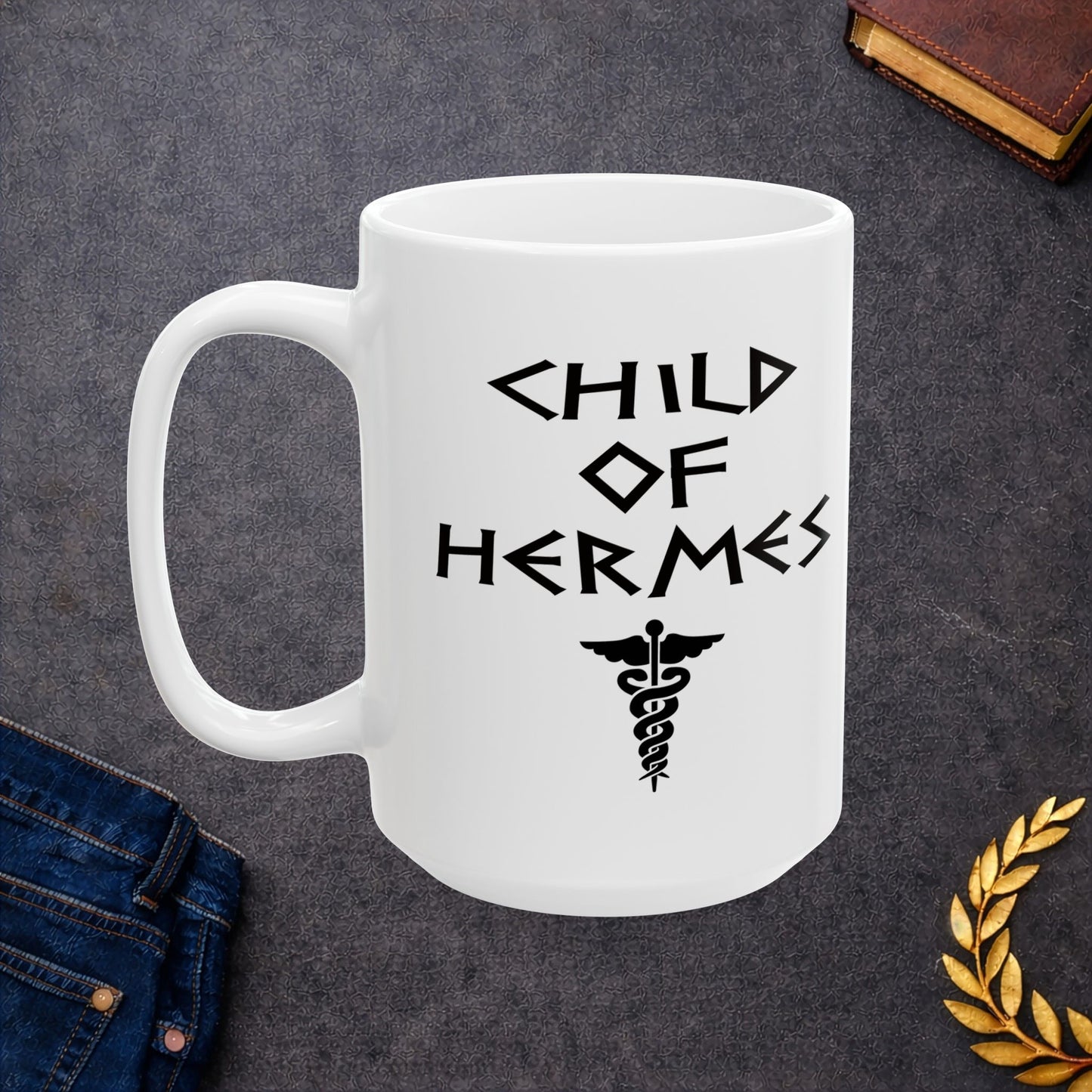 A minimalist black graphic for a white ceramic mug featuring a central caduceus symbol—a winged staff with two snakes entwined around it. Above the symbol, the text "CHILD OF HERMES" is displayed in a sharp, angular font inspired by ancient Greek stone carvings. The entire design is rendered in a clean, high-contrast black outline.