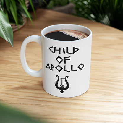 White ceramic mug featuring a minimalist, Greek-inspired graphic in black ink on a white background. The design reads 'CHILD OF APOLLO' in a stylized, angular font, positioned above a clean, line-art graphic of a classical lyre.