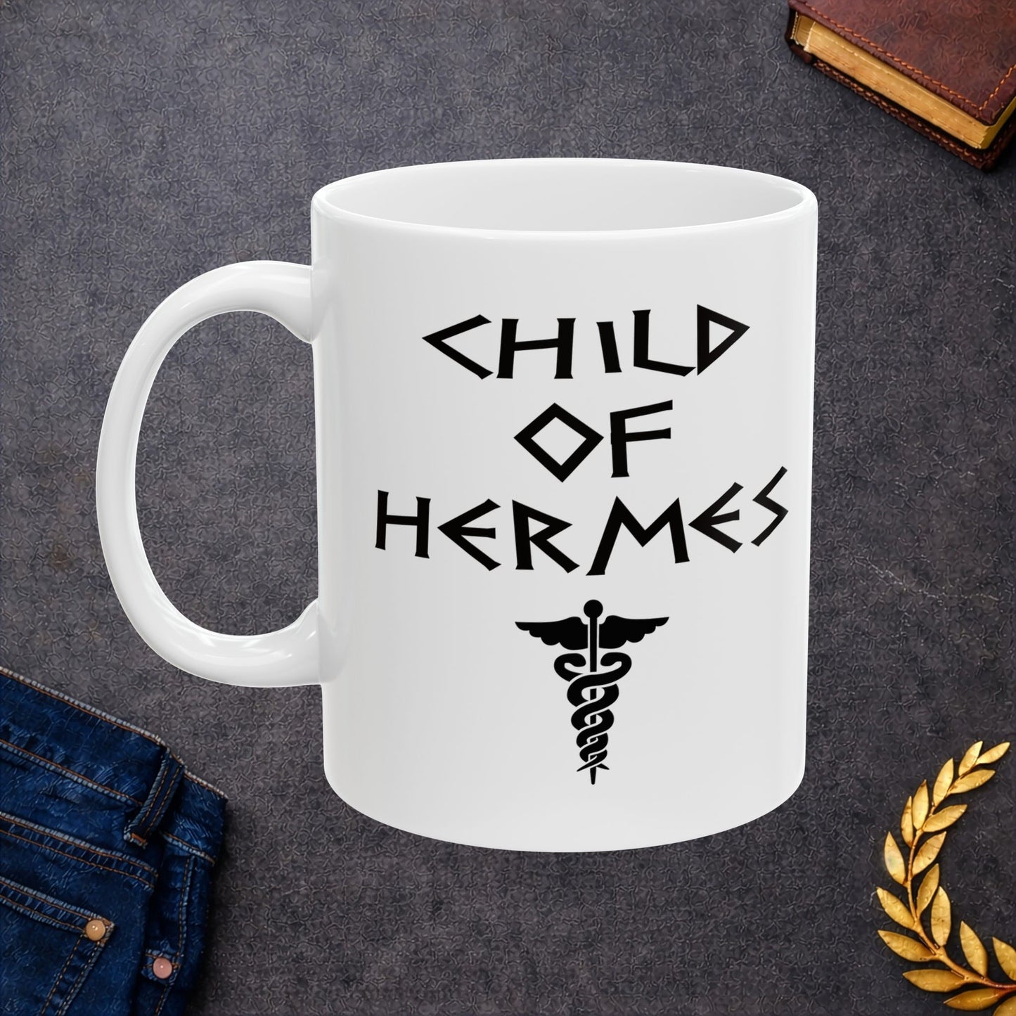 A minimalist black graphic for a white ceramic mug featuring a central caduceus symbol—a winged staff with two snakes entwined around it. Above the symbol, the text "CHILD OF HERMES" is displayed in a sharp, angular font inspired by ancient Greek stone carvings. The entire design is rendered in a clean, high-contrast black outline.