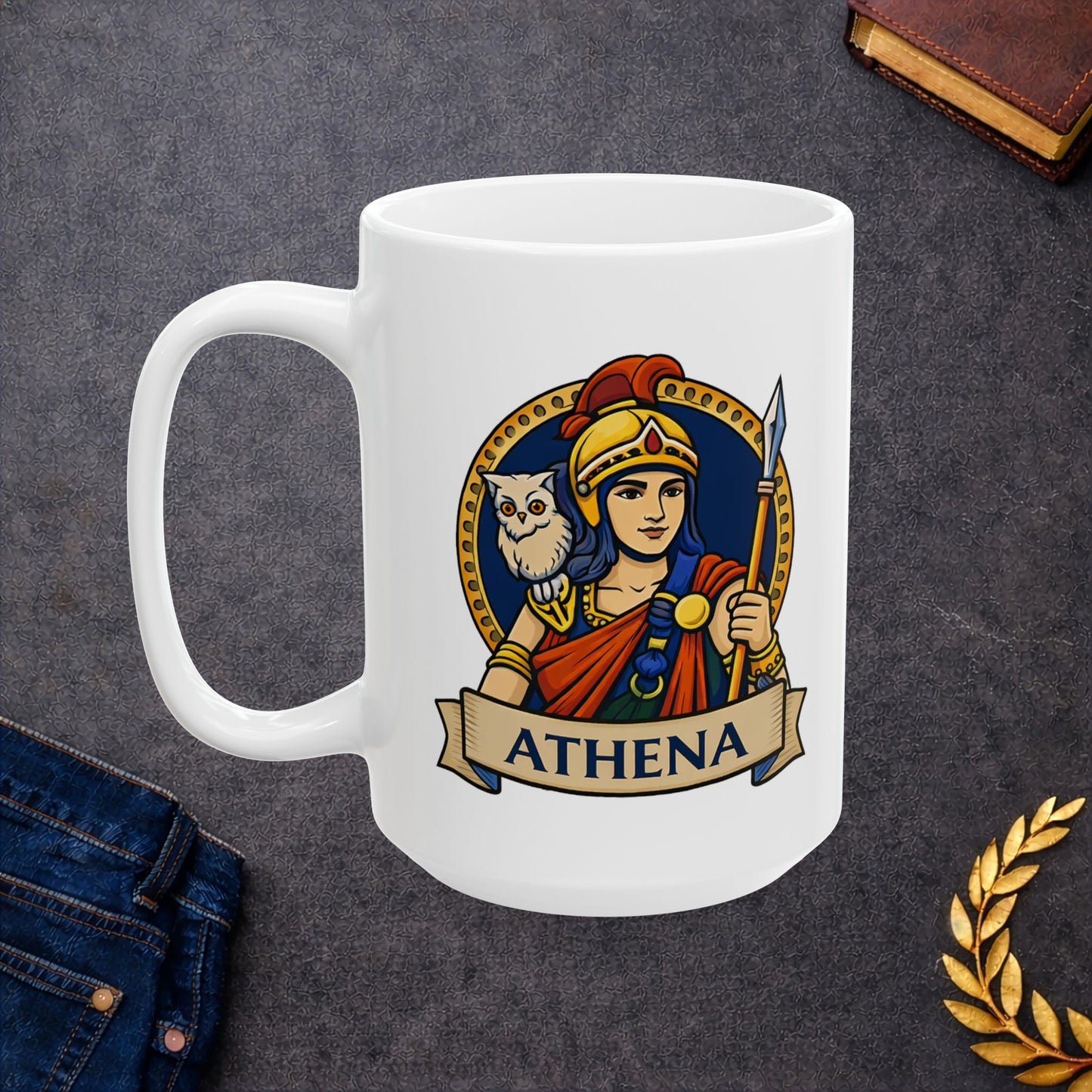 White ceramic mug with a vibrant, circular emblem featuring the Greek goddess Athena. She wears a golden helmet with a red crest and holds a spear, with a small white owl perched on her shoulder. The design is set against a dark blue background with a gold dotted border. A parchment-style banner at the bottom displays the name "ATHENA" in bold capital letters. The illustration has a clean, modern vector art style.