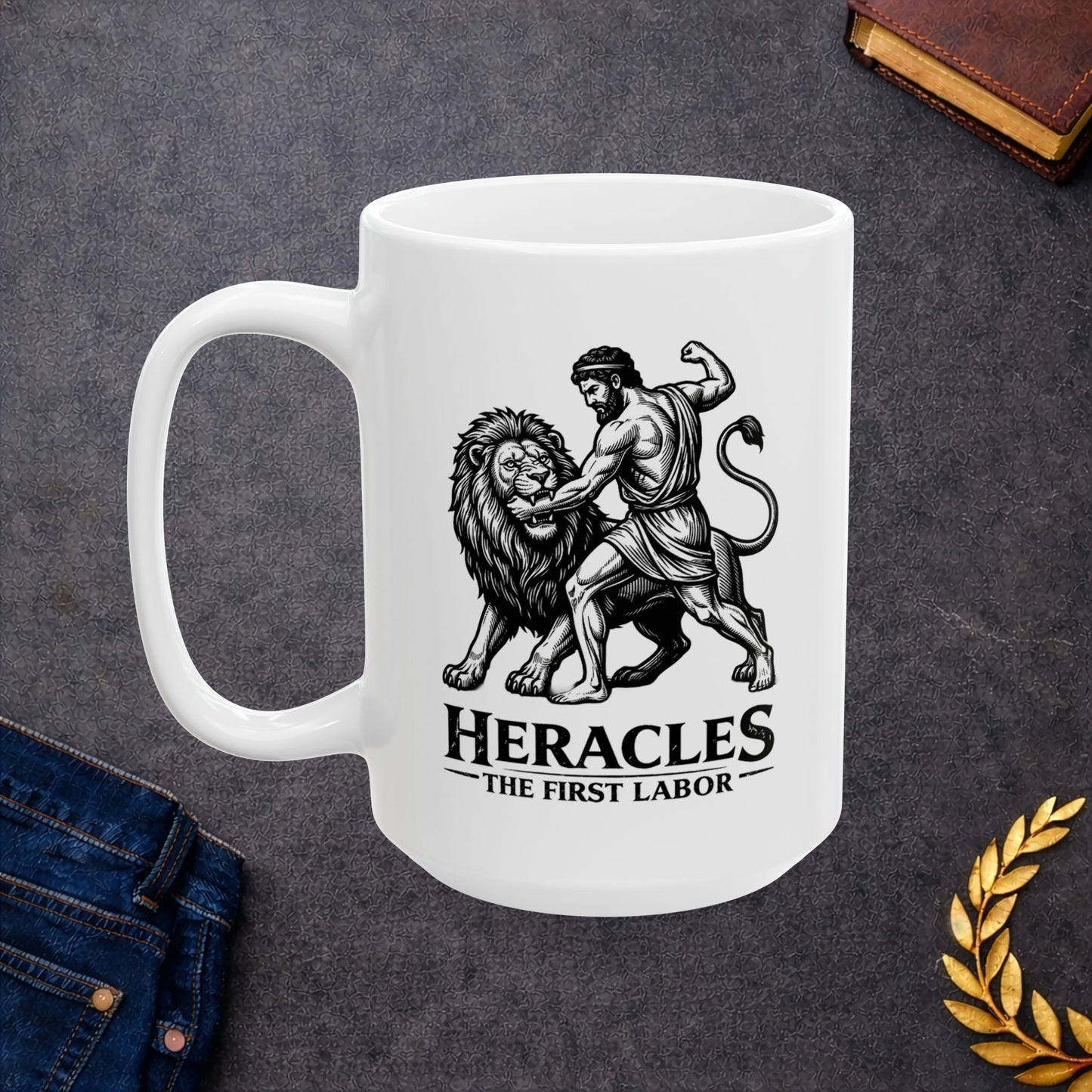 White ceramic mug with a striking black-and-white linocut illustration depicting the Greek hero Heracles wrestling the Nemean Lion. The muscular hero forces his arm into the lion’s open jaws while raising his fist to strike. Below the dynamic scene, bold text reads "HERACLES" followed by a sub-caption that reads "THE FIRST LABOR." The design has a classic, high-contrast vintage woodcut engraving style.