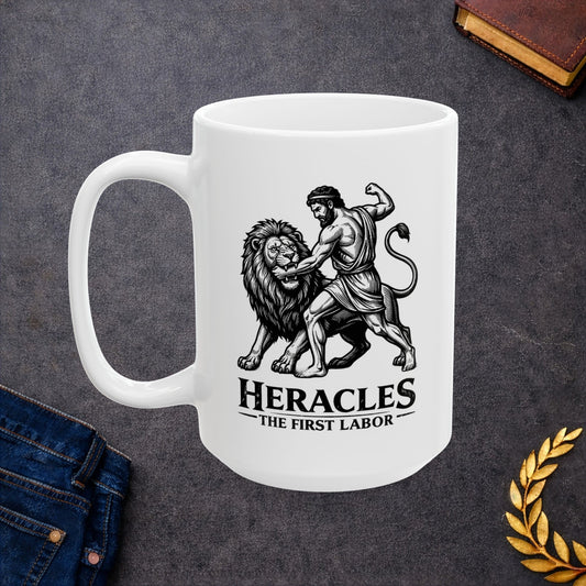 White ceramic mug with a striking black-and-white linocut illustration depicting the Greek hero Heracles wrestling the Nemean Lion. The muscular hero forces his arm into the lion’s open jaws while raising his fist to strike. Below the dynamic scene, bold text reads "HERACLES" followed by a sub-caption that reads "THE FIRST LABOR." The design has a classic, high-contrast vintage woodcut engraving style.