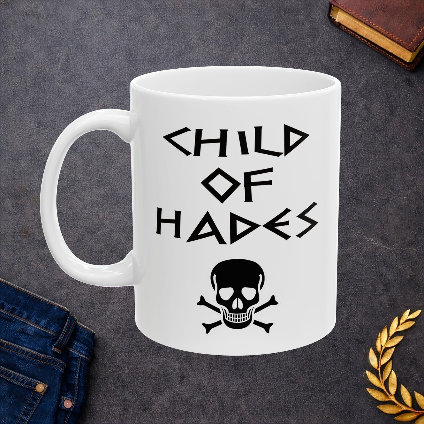 A bold, dark-themed graphic for a white ceramic mug. The design features a large, detailed outline of a skull and crossbones at the center. Above the skull, the words "CHILD OF HADES" are written in a sharp, ancient Greek-inspired angular font. The entire design is rendered in a clean, high-contrast black outline style.