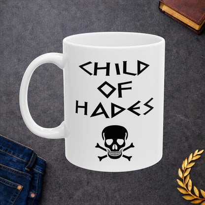 A bold, dark-themed graphic for a white ceramic mug. The design features a large, detailed outline of a skull and crossbones at the center. Above the skull, the words "CHILD OF HADES" are written in a sharp, ancient Greek-inspired angular font. The entire design is rendered in a clean, high-contrast black outline style.