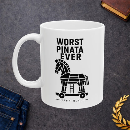 White ceramic mug with a minimalist black-and-white graphic featuring a stylized, geometric silhouette of the Trojan Horse on a wheeled platform with a small ladder underneath. Stacked above the horse, bold black text reads "WORST PIÑATA EVER." Centered below the wheels, a sub-caption reads "— 1184 B.C. —" framed by thin horizontal lines. The clean, high-contrast design offers a humorous, modern take on the ancient Greek myth.