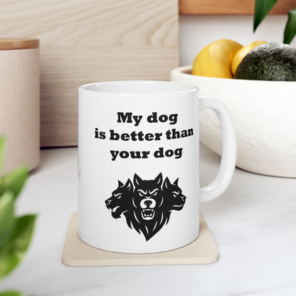 White ceramic mug with a minimalist black-and-white graphic featuring a bold, three-headed Cerberus illustration. The hound of the underworld is shown with snarling expressions and sharp teeth. Above the heads, the phrase "My dog is better than your dog" is written in a heavy, black slab-serif font. The design is a clean, modern take on Greek mythology with a humorous twist.