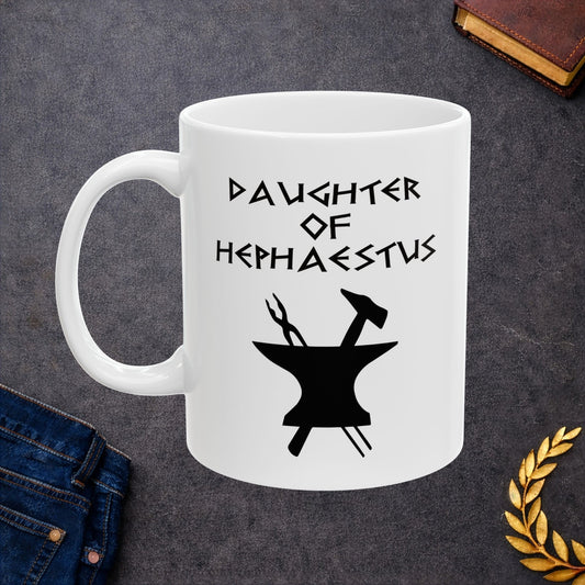 A minimalist black graphic for a white ceramic mug. The design features a central silhouette of a blacksmith's anvil with a hammer and tongs crossed behind it. Above the tools, the text "DAUGHTER OF HEPHAESTUS" is written in a sharp, angular font inspired by ancient Greek inscriptions. The entire illustration is rendered in a clean, solid black style.