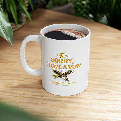 White ceramic mug with a mystical, gold-toned graphic against a dark background featuring the text "SORRY, I HAVE A VOW" in a bold serif font. A golden crescent moon and stars float above the words. Below the main text is a detailed illustration of a crossed bow and arrow surrounded by stardust sparkles, followed by the caption "Hunter of Artemis" framed by decorative gold accents.