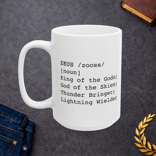A minimalist black graphic for a white ceramic mug, styled as a dictionary entry. The design features the name "ZEUS" in a bold typewriter font, followed by the phonetic pronunciation "/zooss/," the word class "[noun]," and the definition: "King of the Gods; God of the Skies; Thunder Bringer; Lightning Wielder.