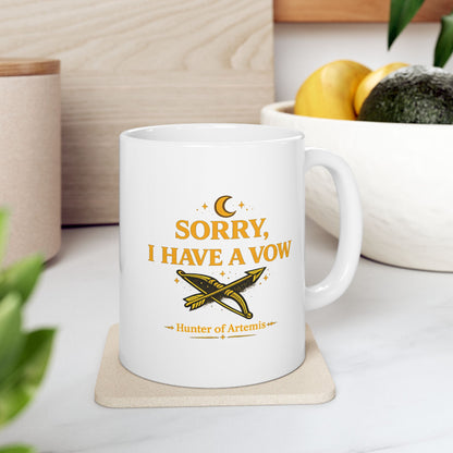 White ceramic mug with a mystical, gold-toned graphic against a dark background featuring the text "SORRY, I HAVE A VOW" in a bold serif font. A golden crescent moon and stars float above the words. Below the main text is a detailed illustration of a crossed bow and arrow surrounded by stardust sparkles, followed by the caption "Hunter of Artemis" framed by decorative gold accents.