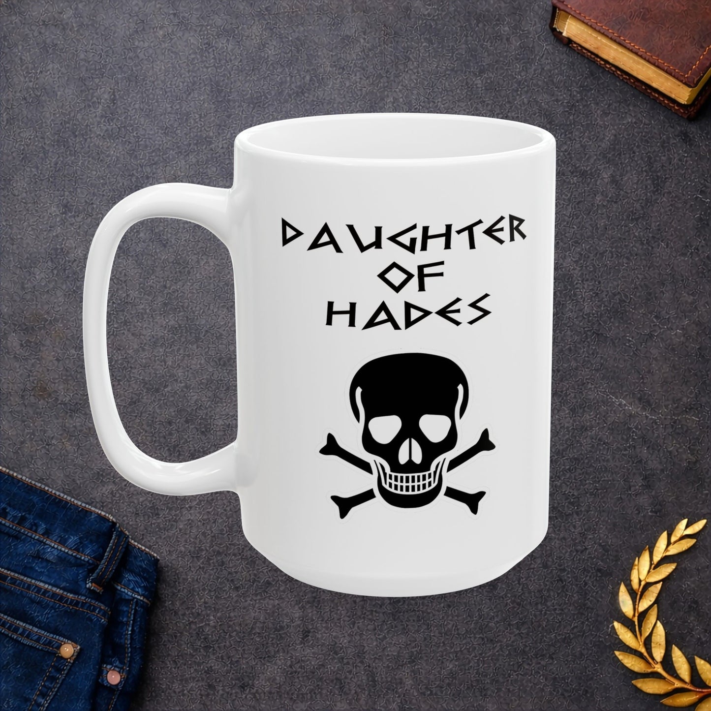A bold, dark-themed graphic for a white ceramic mug. The design features a large, detailed outline of a skull and crossbones at the center. Above the skull, the words "DAUGHTER OF HADES" are written in a sharp, ancient Greek-inspired angular font. The entire design is rendered in a clean, high-contrast black outline style.