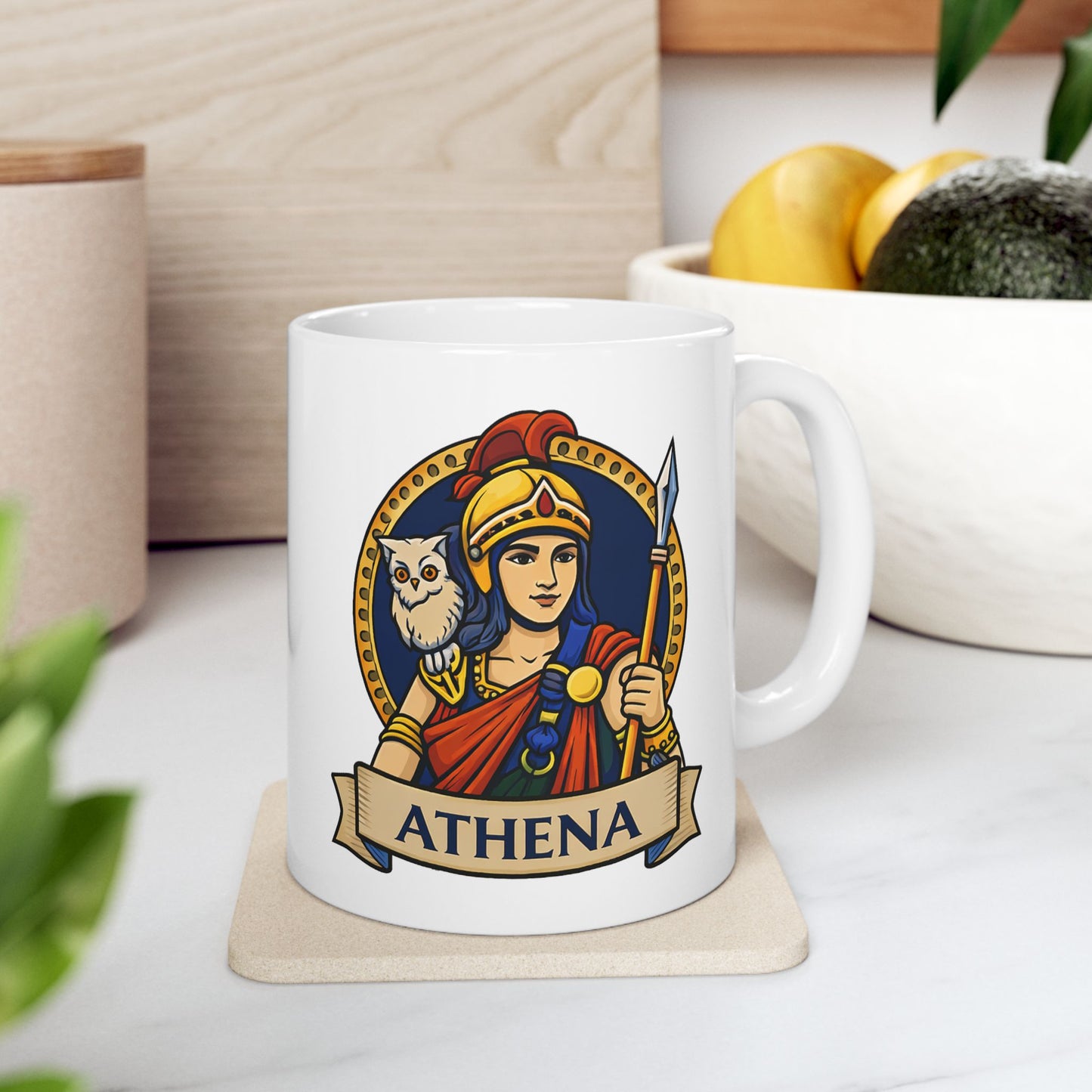 White ceramic mug with a vibrant, circular emblem featuring the Greek goddess Athena. She wears a golden helmet with a red crest and holds a spear, with a small white owl perched on her shoulder. The design is set against a dark blue background with a gold dotted border. A parchment-style banner at the bottom displays the name "ATHENA" in bold capital letters. The illustration has a clean, modern vector art style.