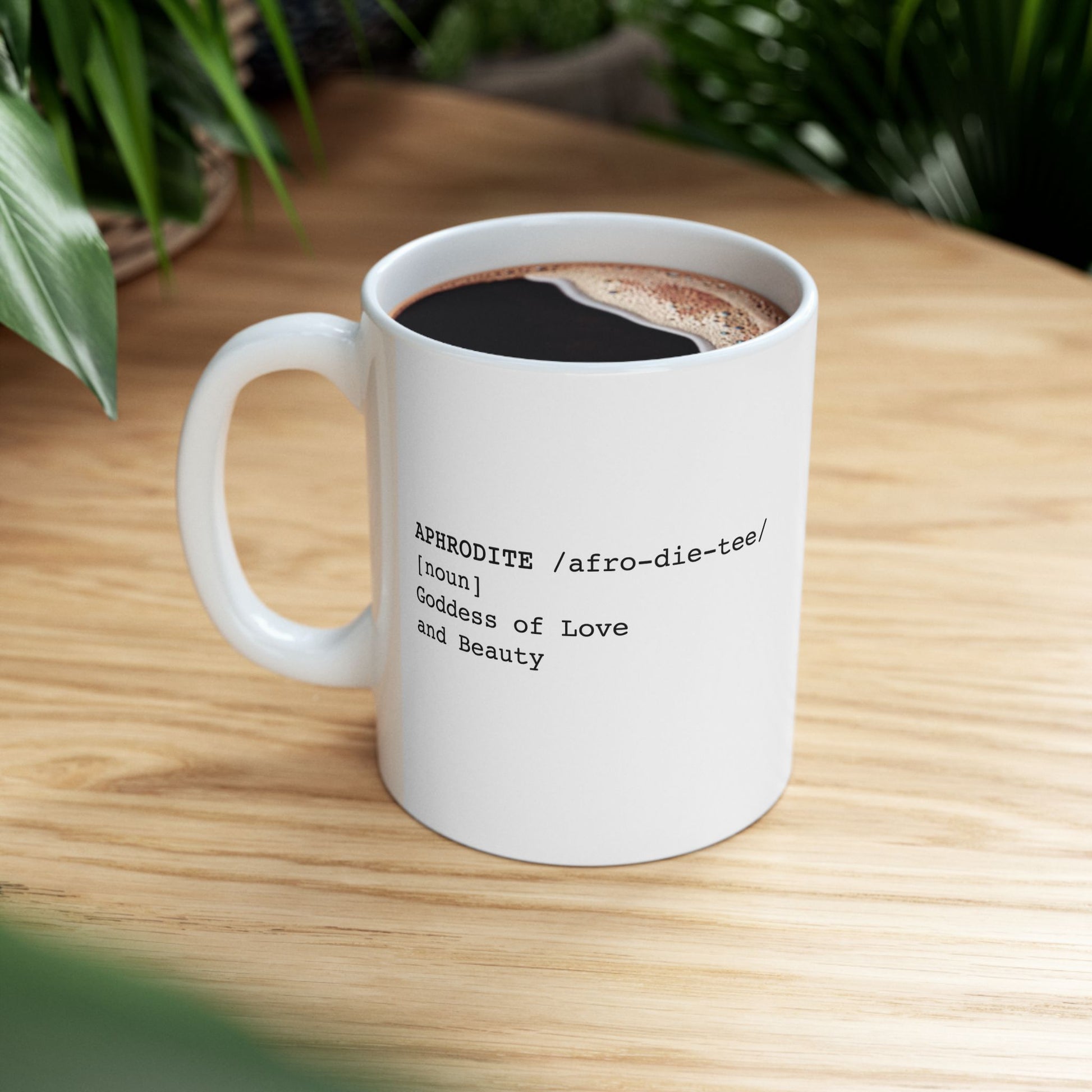 White ceramic mug featuring a dictionary-style definition graphic in black text on a white background. The text reads: 'APHRODITE /afro-die-tee/ [noun] Goddess of Love and Beauty.