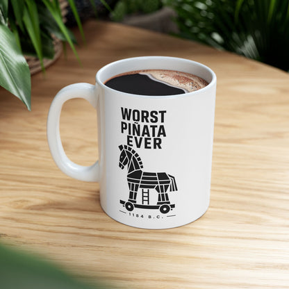 White ceramic mug with a minimalist black-and-white graphic featuring a stylized, geometric silhouette of the Trojan Horse on a wheeled platform with a small ladder underneath. Stacked above the horse, bold black text reads "WORST PIÑATA EVER." Centered below the wheels, a sub-caption reads "— 1184 B.C. —" framed by thin horizontal lines. The clean, high-contrast design offers a humorous, modern take on the ancient Greek myth.
