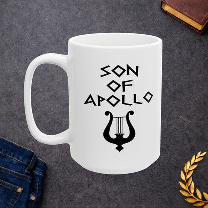 White ceramic mug featuring a minimalist, Greek-inspired graphic in black ink on a white background. The design reads 'SON OF APOLLO' in a stylized, angular font, positioned above a clean, line-art graphic of a classical lyre.