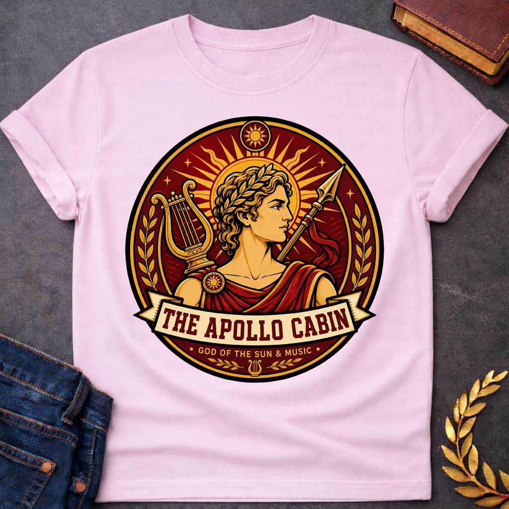 Light Pink t-shirt with a Apollo Greek mythology cabin design featuring the god of the sun and music wearing a golden laurel crown, framed by a radiant sun, lyre, spear, stars, and laurel branches. Rich red, gold, and cream circular camp-style emblem includes the text “The Apollo Cabin” and “God of the Sun & Music.
