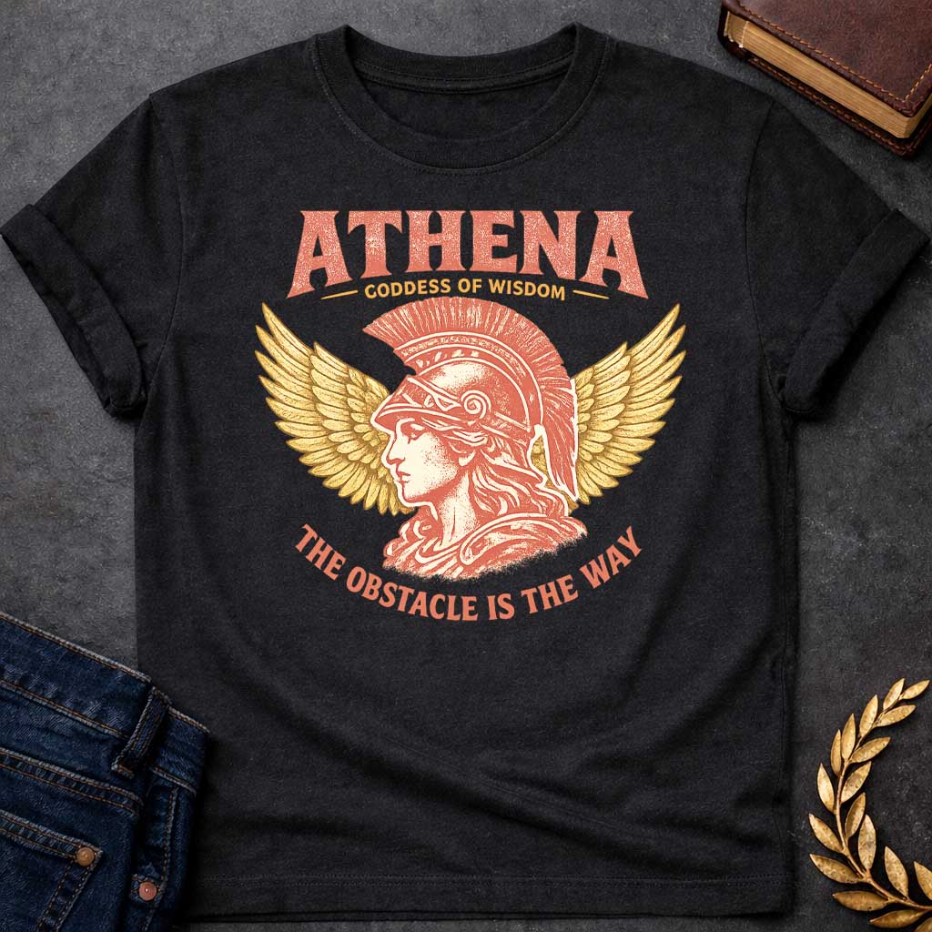 Black t-shirt graphic featuring a side-profile illustration of Athena wearing a Corinthian helmet with a red plume, flanked by large golden wings. Text reads "ATHENA – Goddess of Wisdom" arched above and "The Obstacle Is the Way" curved below, in a vintage Greek mythology style with rose and gold tones