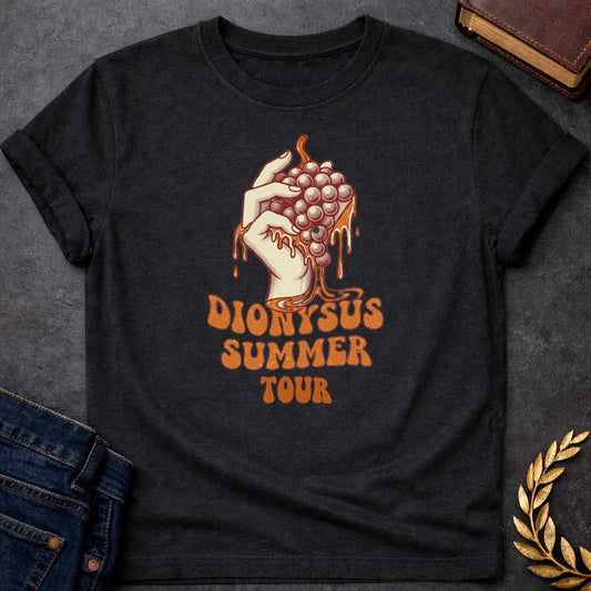 Black T-shirt graphic featuring a vintage-style illustration of a hand squeezing a bunch of grapes with juice dripping down, rendered in a retro halftone print style in cream and burnt orange tones.  Bold groovy retro lettering below reads "Dionysus Summer Tour," inspired by 1970s rock concert merchandise design