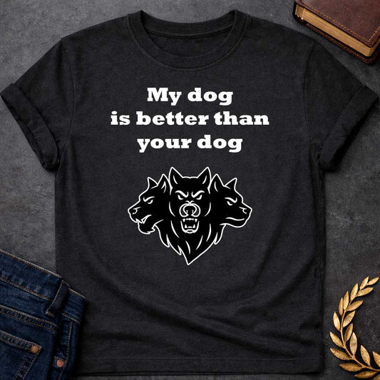 Black T-shirt graphic in black and white featuring bold serif text reading "My dog is better than your dog" above a flat black silhouette illustration of Cerberus, the three-headed dog of the underworld, with the center head facing forward snarling and the two side heads in profile, in a humorous nod to Hades from Greek mythology, designed for a light-coloured shirt