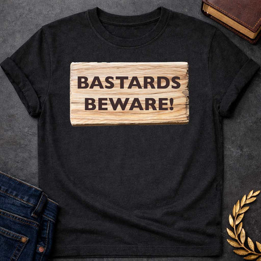 Black T-shirt graphic featuring a realistic illustration of a weathered and splintered wooden plank sign with bold dark brown text reading "Bastards Beware!" in a humorous nod to Hera, the Greek Queen of the Gods, known for her jealous wrath toward Zeus's illegitimate children