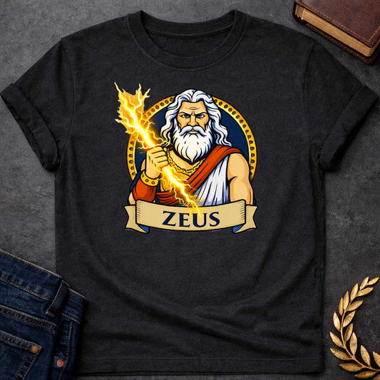 Black T-shirt graphic featuring a vibrant illustrated portrait of Zeus, the Greek King of the Gods, as a powerful older man with long wavy white hair and a full white beard, piercing blue eyes, wearing a white draped robe with a red sash and a gold chain necklace and bracelet, wielding a crackling golden lightning bolt. He is framed within a gold circular border against a navy background, with a scroll banner below reading "Zeus," in a bold tattoo-inspired style with navy, gold, and white tones