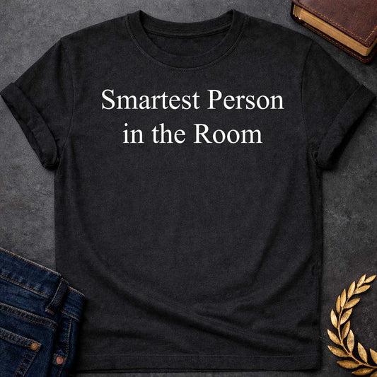 Black T-shirt graphic in white featuring large elegant serif text reading "Smartest Person in the Room" — a confident nod to Athena, the Greek Goddess of Wisdom