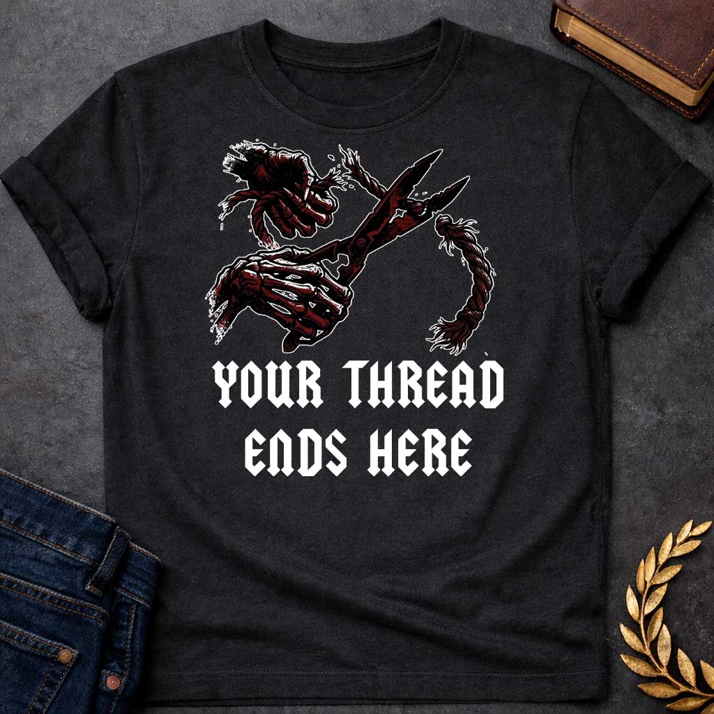 Black T-shirt graphic in black, white, and dark red featuring a dark illustrated scene of two skeletal hands gripping large shears cutting through a thick fraying rope or thread, rendered in a gritty horror-influenced ink style with ink splatter details. Bold heavy metal-style blackletter text below reads "Your Thread Ends Here" — a dark and dramatic reference to Atropos, the eldest of the Moirai, the Greek Fate who cuts the thread of life