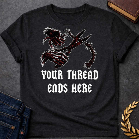 Black T-shirt graphic in black, white, and dark red featuring a dark illustrated scene of two skeletal hands gripping large shears cutting through a thick fraying rope or thread, rendered in a gritty horror-influenced ink style with ink splatter details. Bold heavy metal-style blackletter text below reads "Your Thread Ends Here" — a dark and dramatic reference to Atropos, the eldest of the Moirai, the Greek Fate who cuts the thread of life