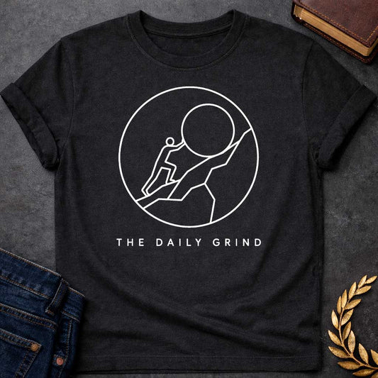 Black T-Shirt with a minimalist white graphic design.  Inside a thin circle is a simple line-art illustration of a stick figure pushing a large boulder up a steep hill, representing the myth of Sisyphus. Below the circle, the text reads "THE DAILY GRIND" in a clean, sans-serif font.