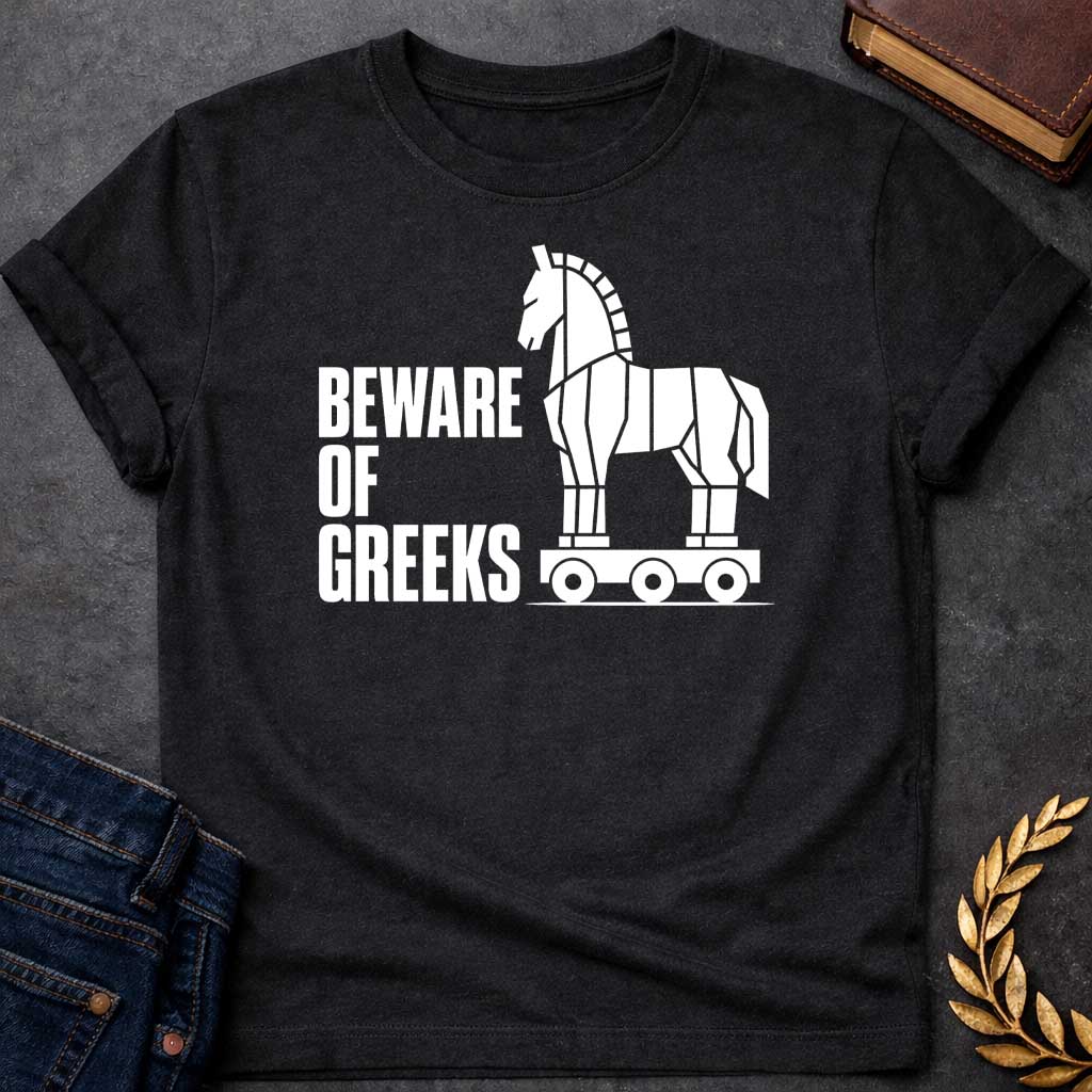 Black T-shirt with a graphic in white featuring bold condensed sans-serif text reading "Beware of Greeks" alongside a flat geometric white silhouette illustration of the Trojan Horse mounted on a wheeled platform — a humorous reference to the Greek legend of the Trojan War