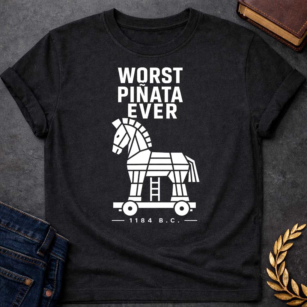 Black T-shirt with a graphic in white featuring bold condensed sans-serif text reading "Worst Piñata Ever" above a detailed flat geometric white silhouette illustration of the Trojan Horse on a wheeled platform with a visible ladder underneath, with a small datestamp below reading "— 1184 B.C. —" — a humorous reference to the Greek legend of the Trojan War