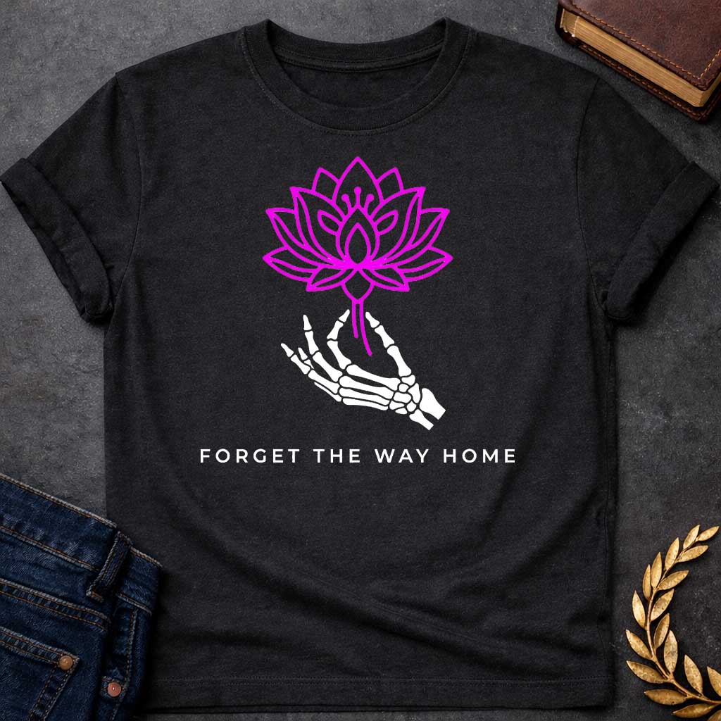 Black T-shirt with a graphic featuring a bold magenta line-art lotus flower held delicately by a white skeletal hand, with spaced bold sans-serif text below reading "Forget the Way Home" — a darkly humorous reference to the Land of the Lotus-Eaters episode in Homer's Odyssey, where Odysseus's crew ate lotus flowers and forgot their desire to return home