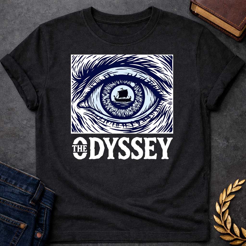 Black T-Shirt with a dramatic graphic design for 'The Odyssey' featuring a stylized eye in navy blue and white. The iris contains a silhouette of an ancient Greek ship with a single sail, surrounded by radiating lines suggesting both an iris pattern and oceanic waves. Swirling, turbulent linework evokes stormy seas and Odysseus's tumultuous journey. Bold serif text reads 'THE ODYSSEY' in white. Combines classical maritime imagery with modern design, emphasizing vision, journey, destiny, and fate.