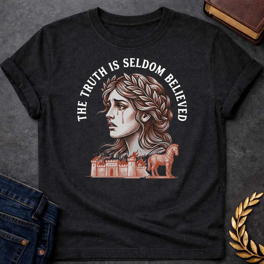 Black T-shirt with a A Greek mythology design featuring a detailed woodblock-engraving style illustration of a crying Cassandra in profile. She wears a laurel wreath, with tears streaming down her face. Arched above her is the text "THE TRUTH IS SELDOM BELIEVED" in a bold white serif font. Below her portrait, a burning ancient city wall and the Trojan Horse are illustrated in a fine-line, terracotta-orange style.