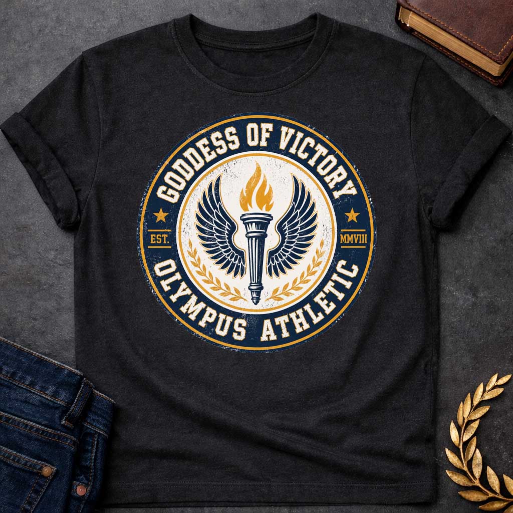 Black T-shirt with an Official athletic seal in navy blue, cream, and gold featuring a torch with large outstretched wings symbolizing Nike, the goddess of victory. Flames burn from the torch. Olive wreaths frame either side. Text reads 'GODDESS OF VICTORY' and 'OLYMPUS ATHLETIC' around the circular border with 'EST. MMVIII.' Distressed vintage texture and gold stars enhance the emblem. Celebrates athletic achievement and triumph.
