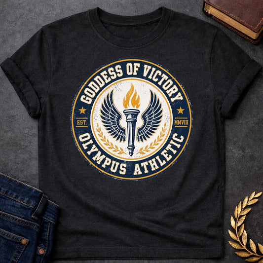 Black T-shirt with an Official athletic seal in navy blue, cream, and gold featuring a torch with large outstretched wings symbolizing Nike, the goddess of victory. Flames burn from the torch. Olive wreaths frame either side. Text reads 'GODDESS OF VICTORY' and 'OLYMPUS ATHLETIC' around the circular border with 'EST. MMVIII.' Distressed vintage texture and gold stars enhance the emblem. Celebrates athletic achievement and triumph.

