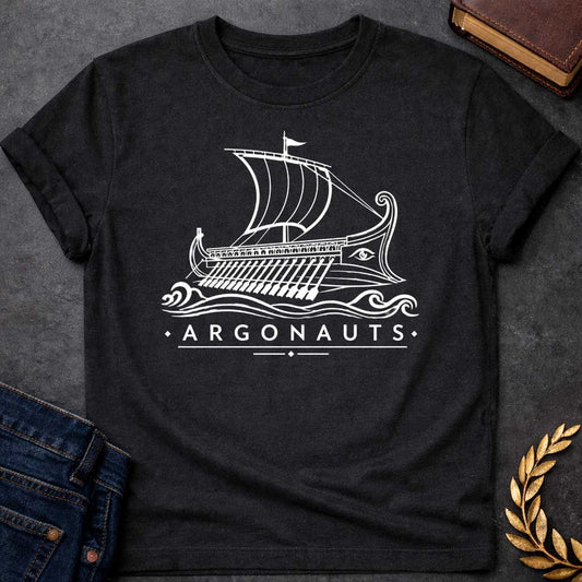 Black T-shirt with A Classical line art rendering of the legendary Argo in navy blue. The Greek ship features billowing sails above a detailed hull with visible oars. Ornate bow and stern decorations frame a protective eye symbol on the hull. Decorative waves flow beneath. Text reads 'Argonauts' with diamond accents. Celebrates the heroic quest of Jason and his crew seeking the golden fleece in ancient Greek mythology.