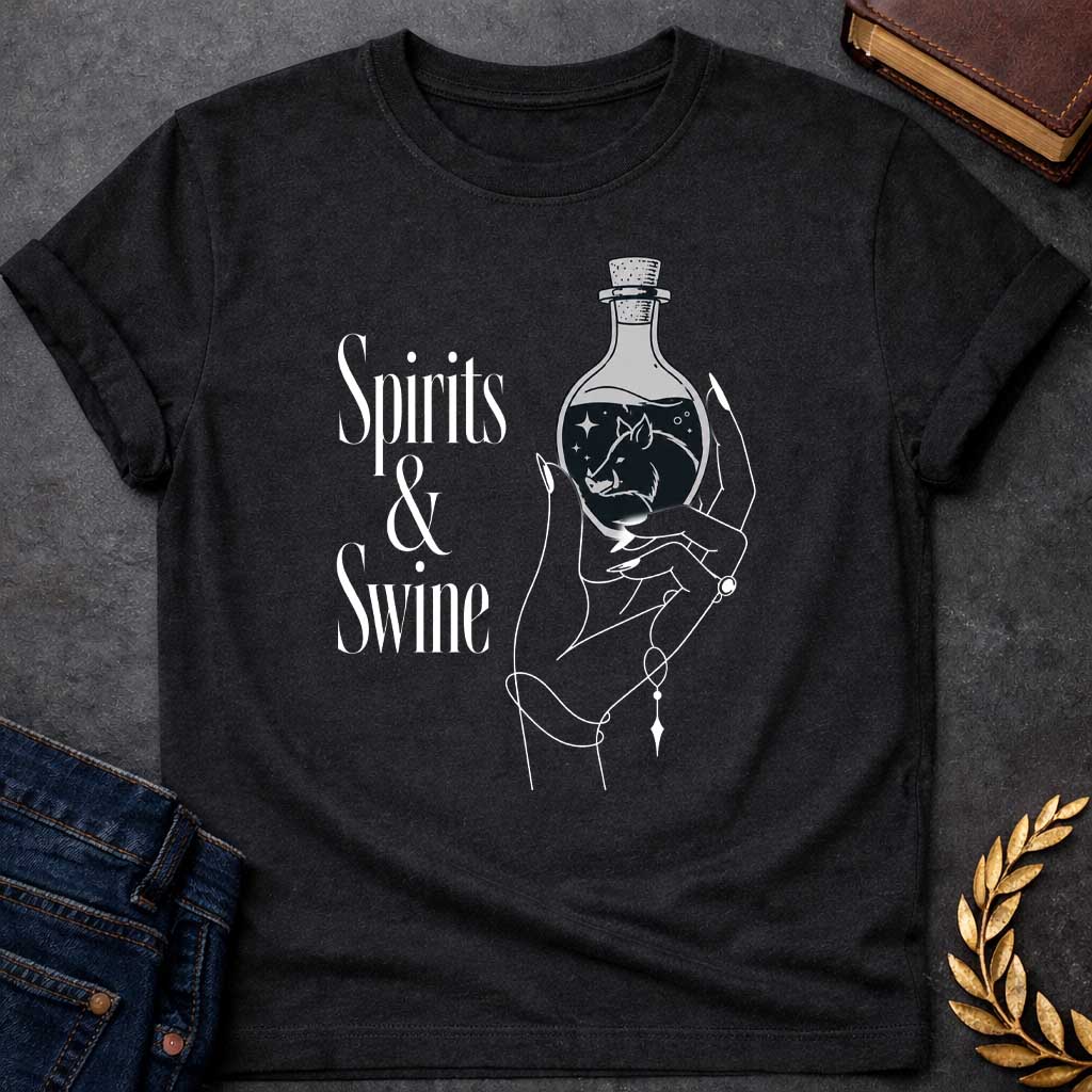 Black T-shirt with a Minimalist line art illustration of a mystical hand holding a potion bottle labeled 'Spirits & Swine.' Inside the dark bottle, a pig silhouette appears amid glowing stars and magical elements. The elegant hand wears decorative bracelets and rings. Black and white aesthetic with witchy, occult vibes. References Circe's legendary enchanted spirits that transformed men into swine. Celebrates ancient magic, potion-making, and mythological transformation with modern witchcraft themes.