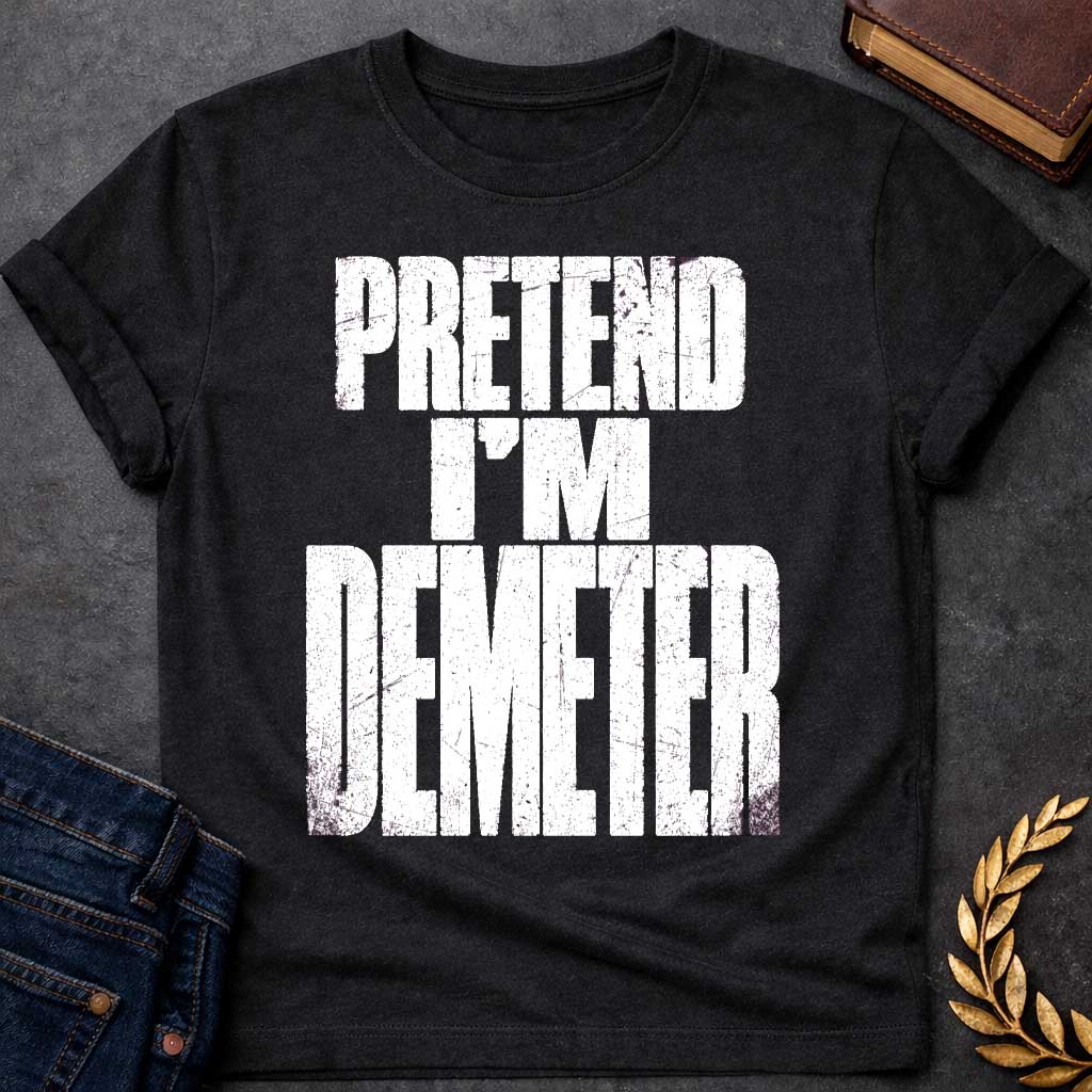 Black t-shirt with a Pretend I’m Demeter Greek mythology design featuring bold distressed white typography on a transparent background. The stacked text reads “PRETEND I’M DEMETER” in a rugged vintage block font, creating a humorous design inspired by Demeter, the Greek goddess of agriculture, harvest, grain, fertility, and the earth.