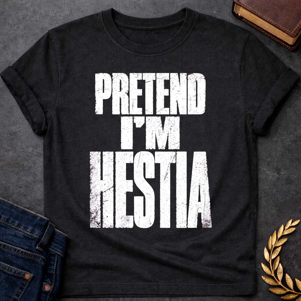 Black t-shirt with a Pretend I’m Hestia Greek mythology design featuring bold distressed white typography on a transparent background. The stacked text reads “PRETEND I’M HESTIA” in a rugged vintage block font, creating a humorous design inspired by Hestia, the Greek goddess of the hearth, home, family, and domestic life.