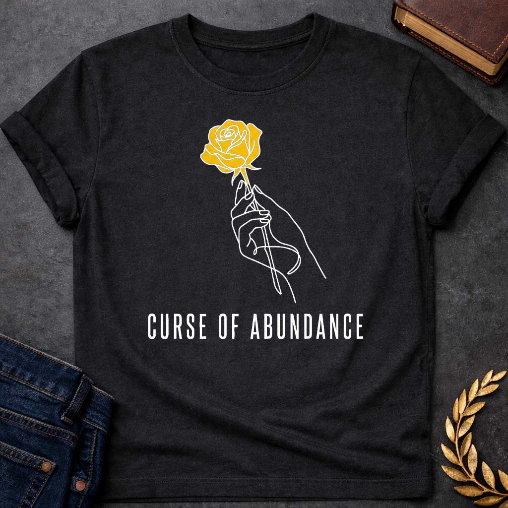 Black t-shirt with A Minimalist Greek mythology design featuring a continuous line-art hand delicately holding a golden rose, symbolizing King Midas' legendary golden touch. Below the illustration, the phrase "Curse of Abundance" appears in clean, modern typography. A simple black-and-gold aesthetic creates an elegant, understated design inspired by the tragic Midas myth.