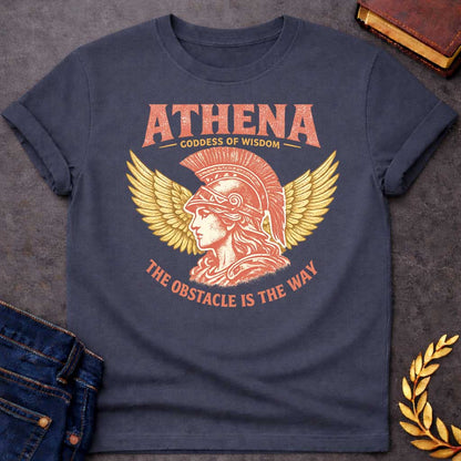 Dark Heather t-shirt graphic featuring a side-profile illustration of Athena wearing a Corinthian helmet with a red plume, flanked by large golden wings. Text reads "ATHENA – Goddess of Wisdom" arched above and "The Obstacle Is the Way" curved below, in a vintage Greek mythology style with rose and gold tones