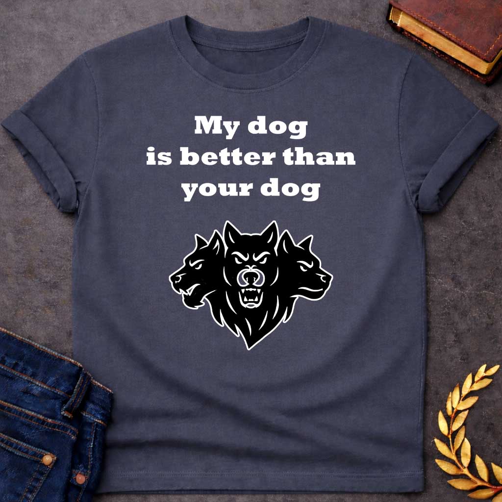 Dark Heather T-shirt graphic in black and white featuring bold serif text reading "My dog is better than your dog" above a flat black silhouette illustration of Cerberus, the three-headed dog of the underworld, with the center head facing forward snarling and the two side heads in profile, in a humorous nod to Hades from Greek mythology, designed for a light-coloured shirt