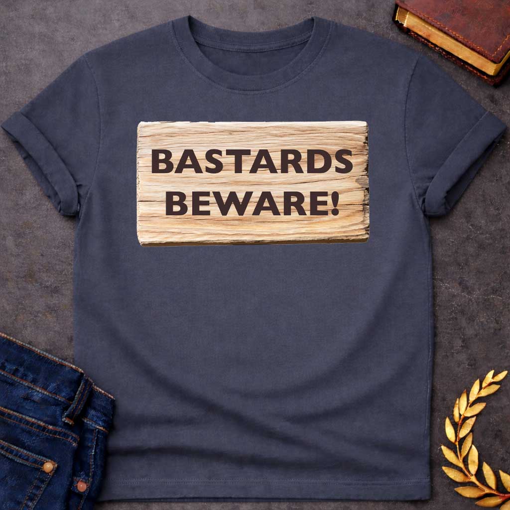 Dark Heather T-shirt graphic featuring a realistic illustration of a weathered and splintered wooden plank sign with bold dark brown text reading "Bastards Beware!" in a humorous nod to Hera, the Greek Queen of the Gods, known for her jealous wrath toward Zeus's illegitimate children
