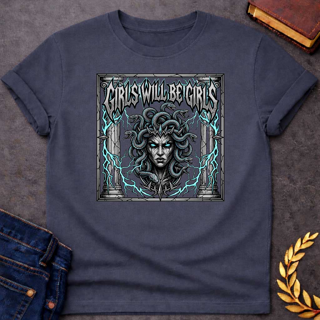 Dark Heather T-shirt graphic in a dark heavy metal style featuring a fierce front-facing illustration of Medusa with glowing teal eyes, a spiked crown, and writhing snakes for hair, surrounded by electric teal lightning bolts and flanked by cracked stone Greek columns, all within a crumbling stone frame. Bold metallic gothic lettering across the top reads "Girls Will Be Girls,"